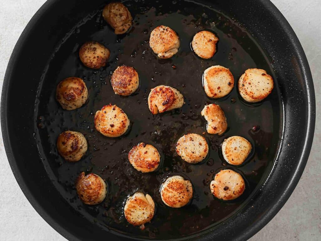 Cooked scallops in a pan before adding the parsley butter.