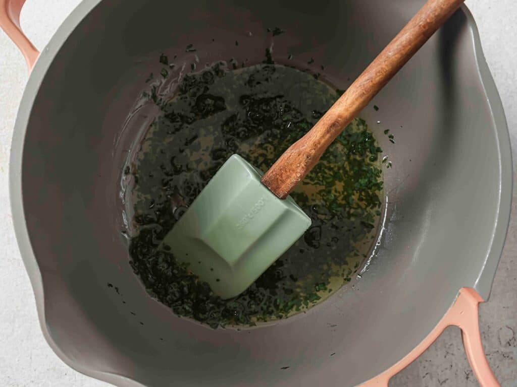 Making parsley butter in a bowl with a spatula.
