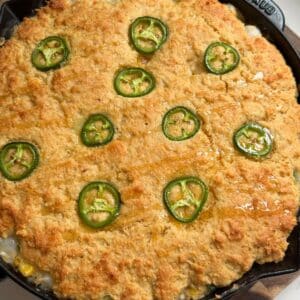 Close-up of a cornbread pot pie topped with cheddar cornbread and sliced jalapeños.