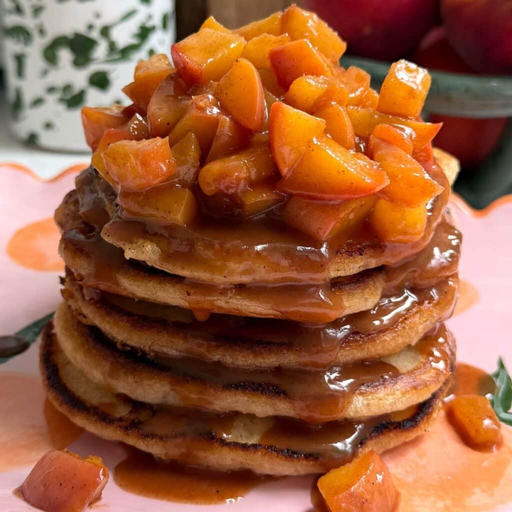 Stack of pancakes with peaches on top.