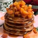 Stack of pancakes with peaches on top.