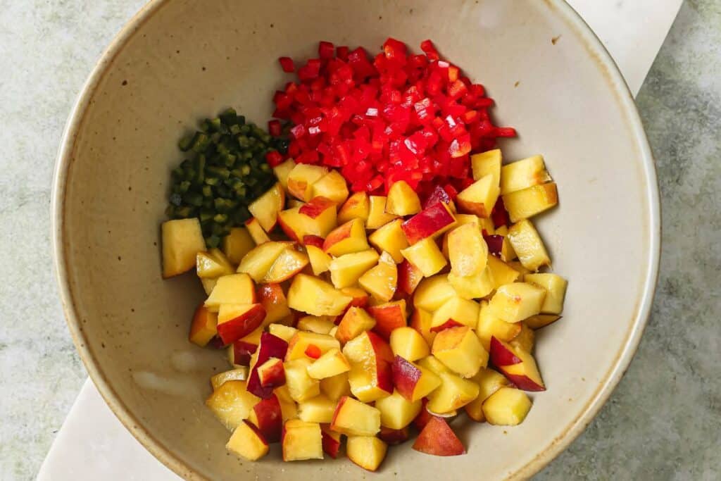 Diced peaches, red peppers, and jalapeno in a mixing bowl.
