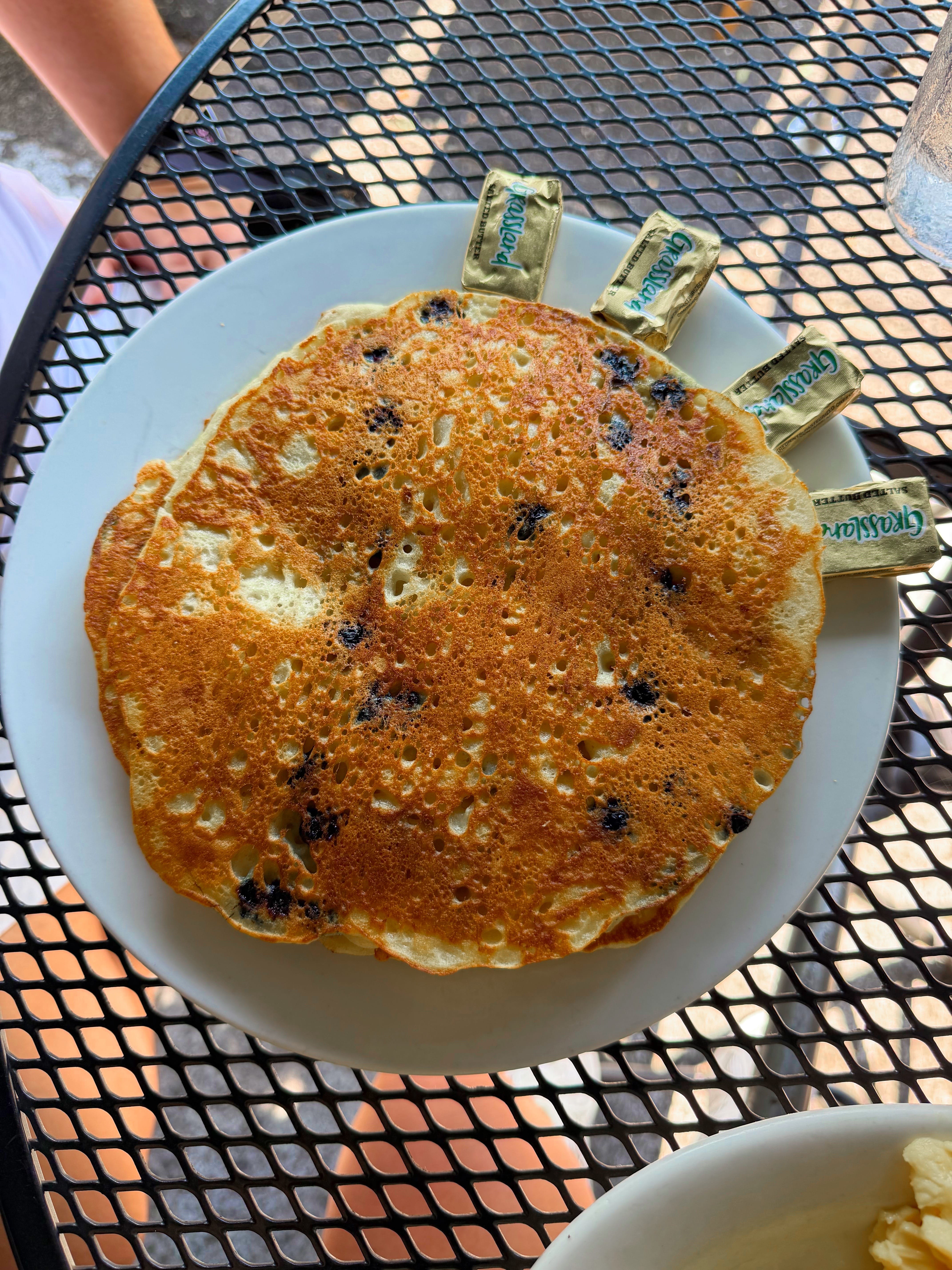 A blueberry pancake on a white plate.