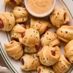 A plate full of air fryer pigs in a blanket with a side of homemade queso dip.