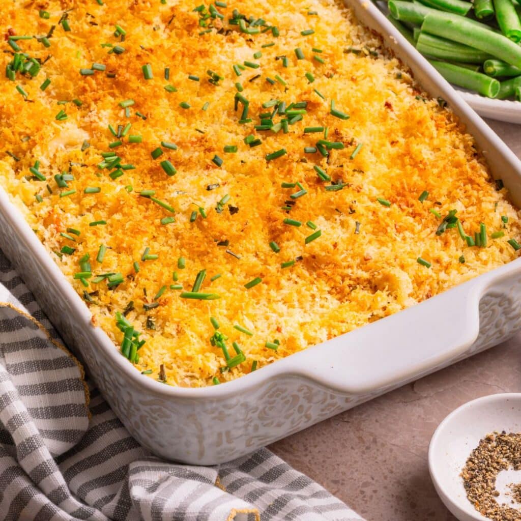 Cheesy mashed potato casserole with a crispy panko topping in a white baking dish.