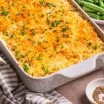 Cheesy mashed potato casserole with a crispy panko topping in a white baking dish.