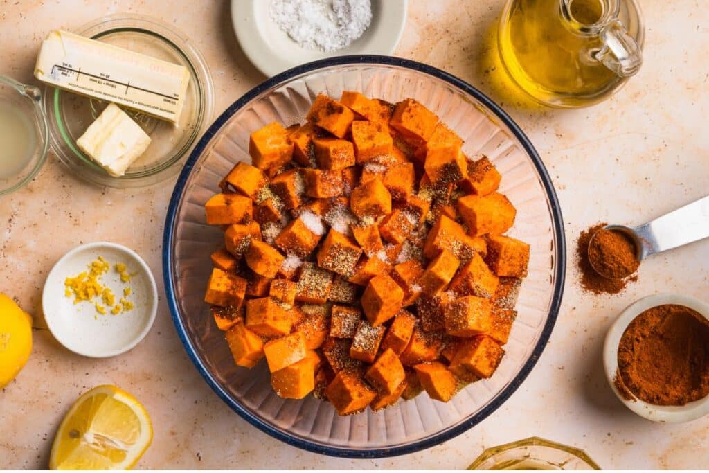 Seasoning the sweet potatoes in a glass bowl. 