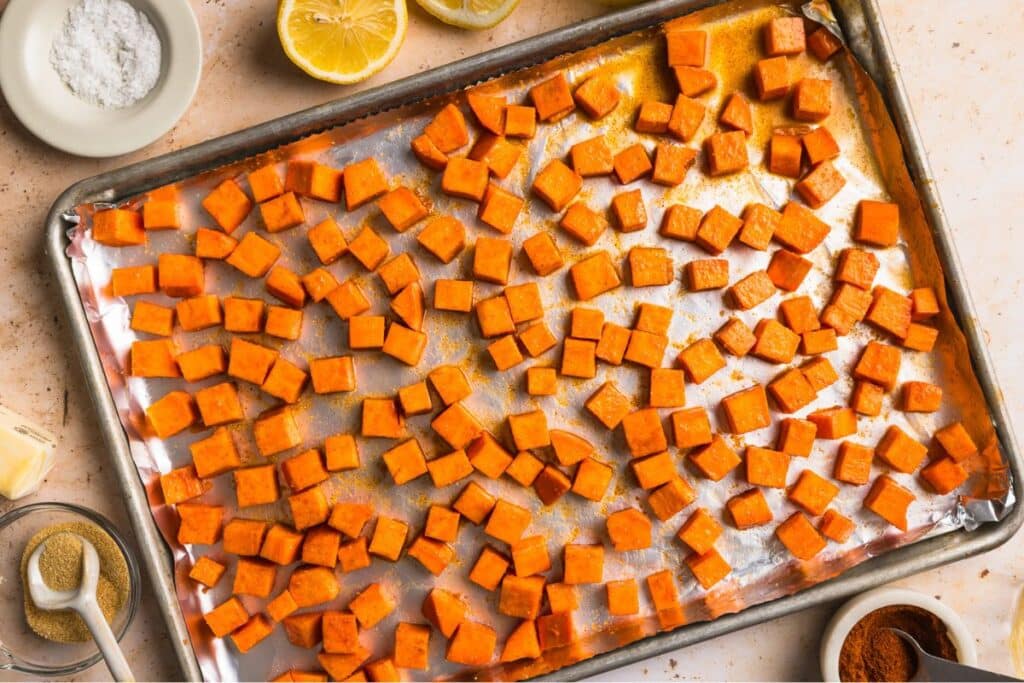 Tossed honey butter sweet potatoes on a baking sheet before cooking. 