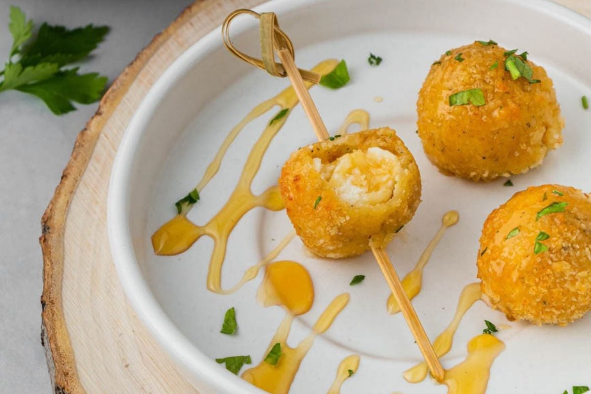 A plate with air fryer fried goat cheese balls drizzled with honey. 
