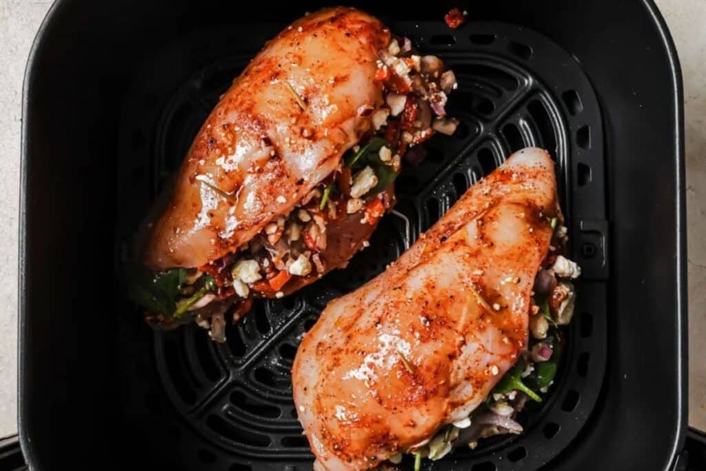 Stuffed chicken breasts in the air fryer basket ready to bake. 