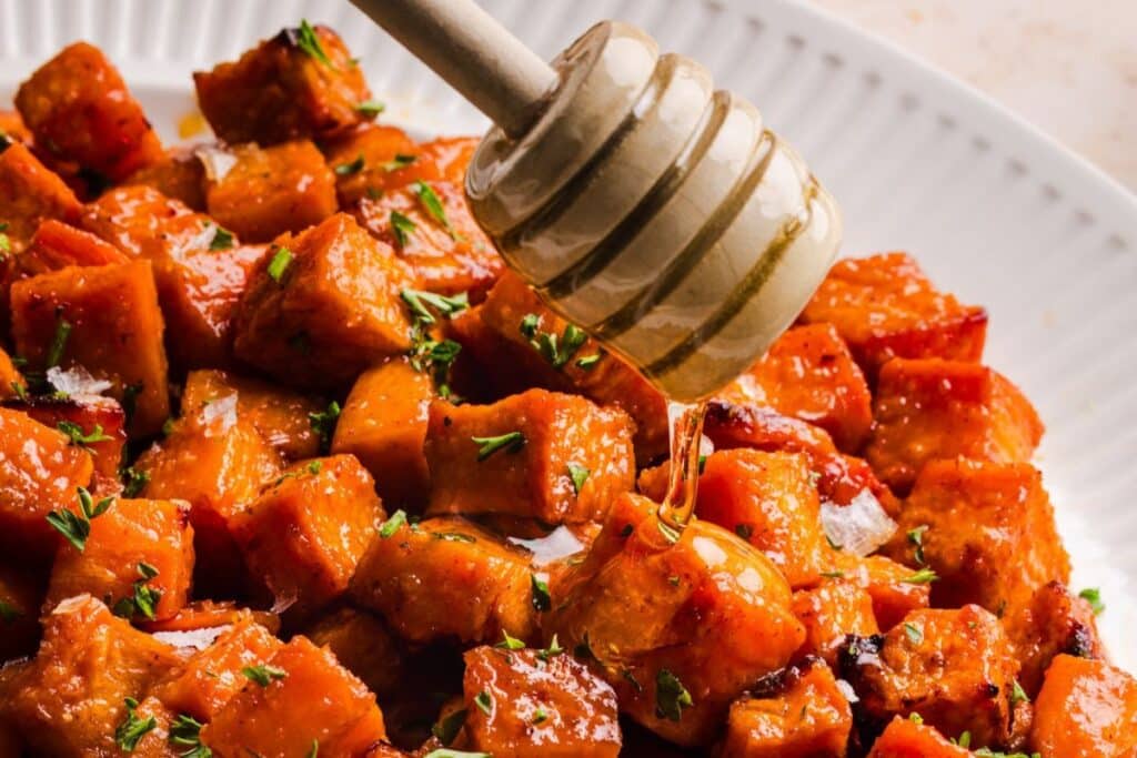 Adding honey butter to the top of roasted sweet potatoes and serving. 