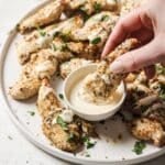 Dipping air fryer chicken tenders in dressing.